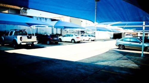 a group of cars parked in a parking lot with umbrellas at Mabruk Barretos Apart Hotel in Barretos
