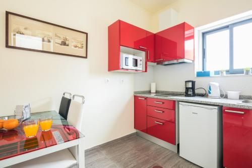 a kitchen with red cabinets and a table with oranges on it at À Francos Artist Painting in Porto