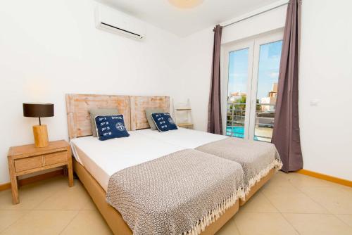 a bedroom with a bed and a large window at Cabanas Gardens by Algartur in Cabanas de Tavira