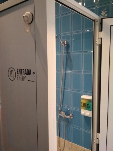 a shower in a bathroom with blue tiles at Casa Do Marabillas in Portomarin