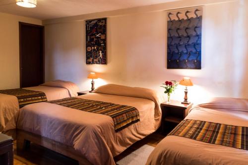 a hotel room with three beds in a room at Casa del Arupo in Quito