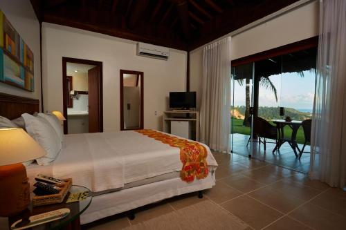 a bedroom with a bed and a view of a patio at Gungaporanga Hotel in Barra de São Miguel