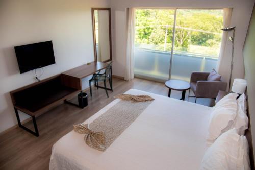 een slaapkamer met een bed, een bureau en een televisie bij 7 Saltos Resort in Salto del Guairá