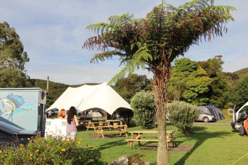 a woman standing next to a picnic table and a tent at Russell-Orongo Bay Holiday Park in Russell