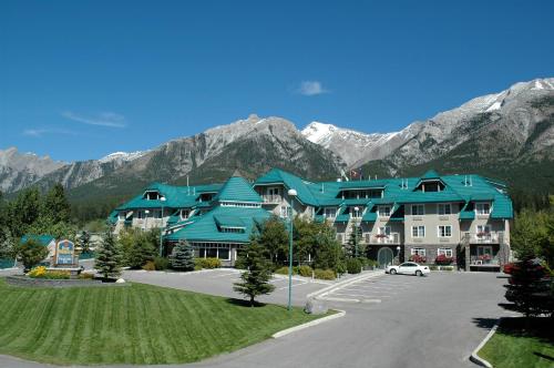 a large building with blue roofs in front of mountains at Pocaterra Inn & Waterslide in Canmore