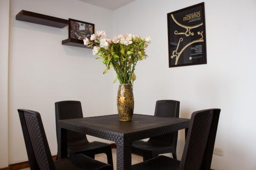 uma mesa preta com um vaso de flores em HYG Hotel em Pasto