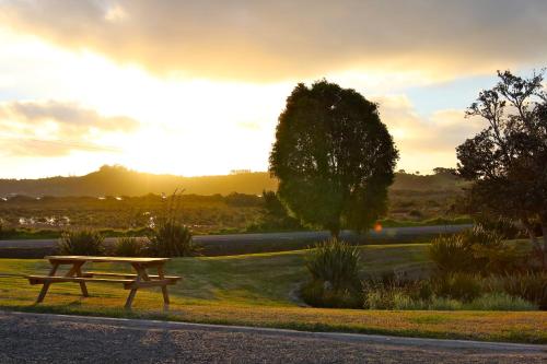 a picnic table in a park with the sunset in the background at Russell-Orongo Bay Holiday Park in Russell