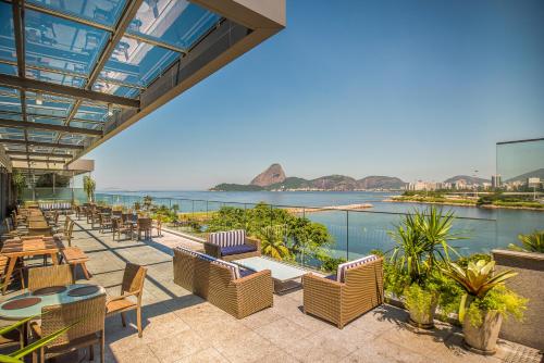 a patio with tables and chairs and a view of the water at Prodigy Santos Dumont by Wish in Rio de Janeiro