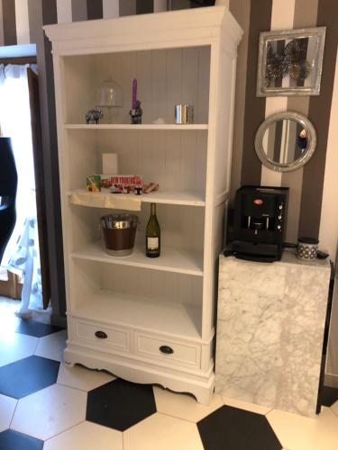 a white book shelf with a bottle of wine at Dimora del Podestà in CastellʼArquato