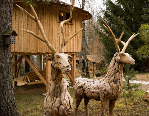 two statues of deer standing next to a tree at Les Cabanes Du Saleve in Collonges-sous-Salève