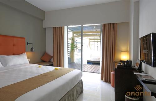 Habitación de hotel con cama y puerta corredera de cristal en Ananta Legian Hotel en Legian