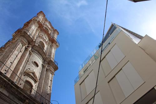 a building with a clock tower next to a building at Málaga Premium Hotel in Málaga