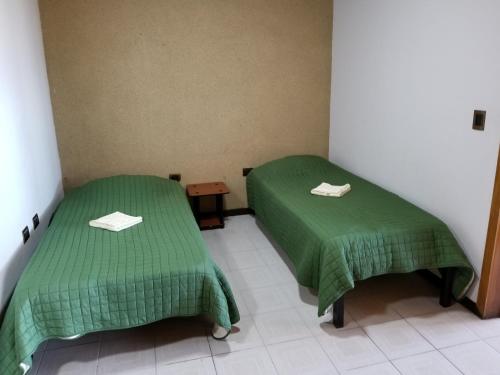 two beds in a room with green sheets at Hotel Monte Campana Escazu in San José