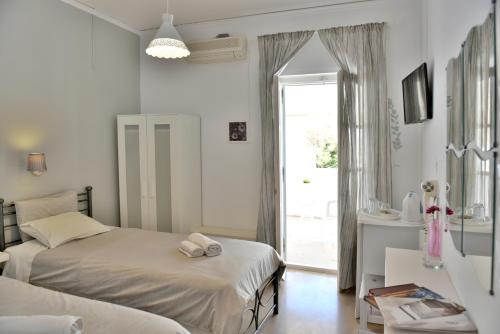 a bedroom with two beds and a window and a mirror at Guesthouse Corali in Hydra