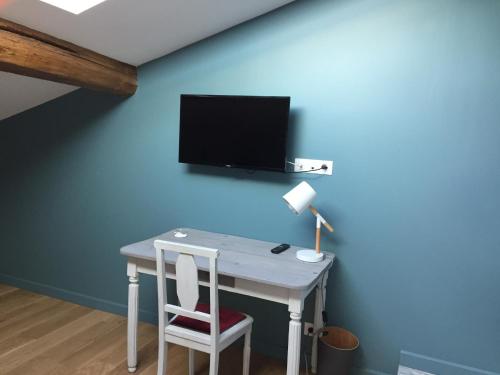 a desk with a chair and a tv on a blue wall at La Garoffe in Pibrac