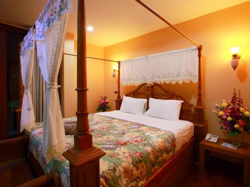 a bedroom with a canopy bed with white pillows at At Chiang Mai Hotel in Chiang Mai