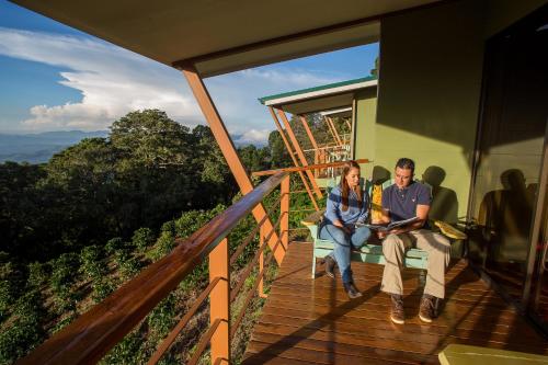 a man and woman sitting on the porch of a house at Chayote Lodge in Zarcero