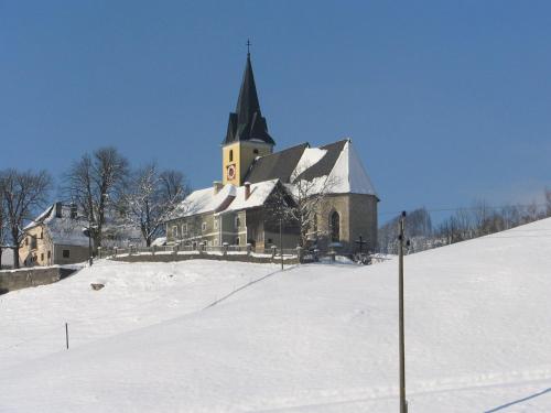 a church with a steeple on top of a snow covered hill at Ferienhof Unterführholzergut in Klaus