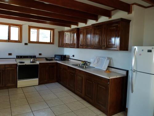 a kitchen with wooden cabinets and a white refrigerator at Hotel Monte Campana Escazu in San José