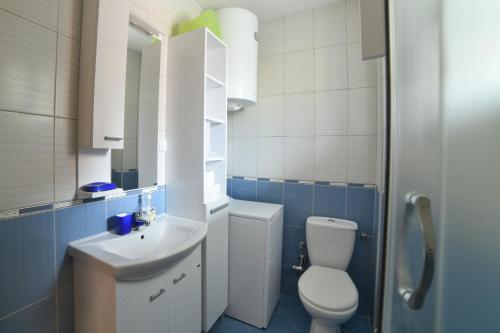 a blue and white bathroom with a toilet and a sink at Tuna Apartments in Dobra Voda