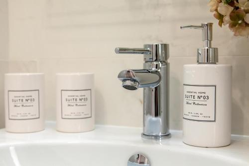 a bathroom sink with three bottles of white kaps at Appartamento Via Acquati 12 - Monolocale 1 in Cormano