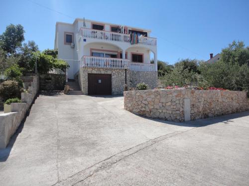 a large house with a stone wall and a driveway at Apartments Ema in Sali