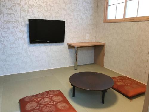 a living room with a table and a tv on the wall at Hotel Famitic Nikko Station in Nikko