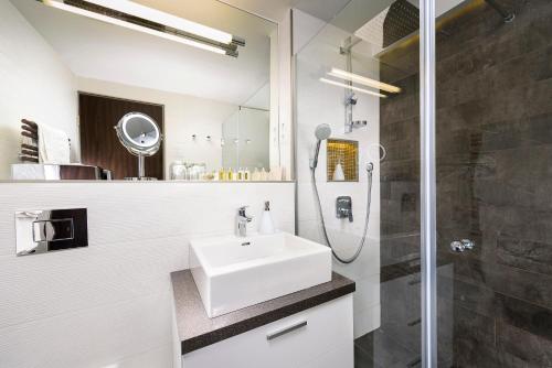 a white bathroom with a sink and a shower at Opera Garden Hotel & Apartments in Budapest