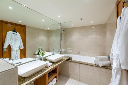 a bathroom with two sinks and a tub and a mirror at Plymouth International in New Plymouth