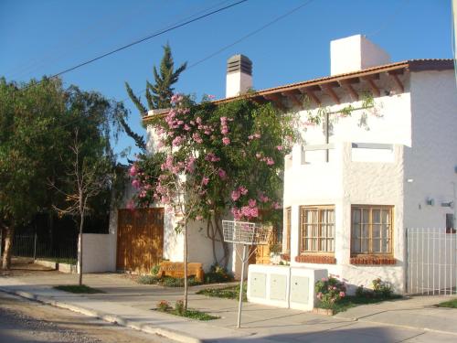 a white house with pink flowers on the side of it at Calfulauquen in Las Grutas