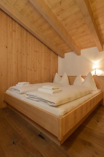 a large bed in a room with wooden walls at Hotel St. Florian - Kaprun in Kaprun