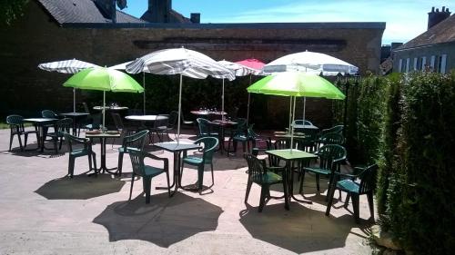 een groep tafels en stoelen met groene en witte parasols bij L'Auberge l'Orée du Bois in Aillières