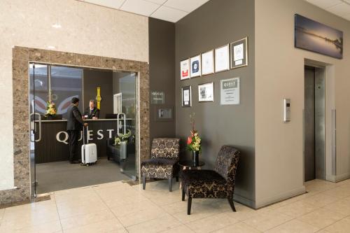 a man standing at a reception desk in a lobby at Quest Rotorua Central in Rotorua