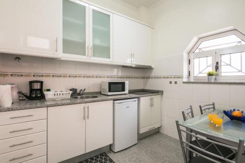 a kitchen with white cabinets and a table at À Francos Painting Artist 2 in Porto