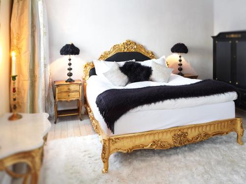 a bedroom with a gold and white bed with pillows at Görvälns Slott in Järfälla