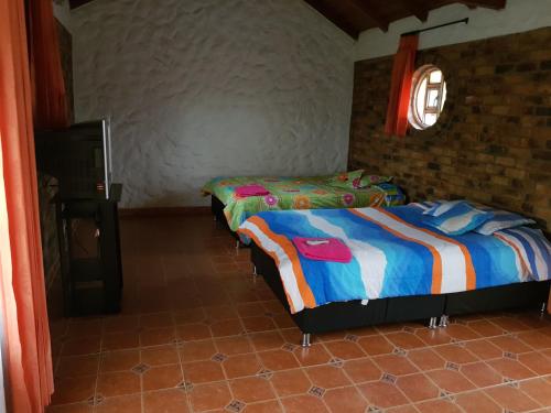 a bedroom with two beds and a brick wall at Finca Villa Patricia in Paipa