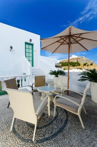 a patio with chairs and a table and an umbrella at Xenones Lindos in Líndos