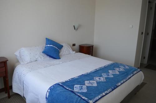 a bed with a blue and white blanket on it at Departamento Concepción III in Concepción