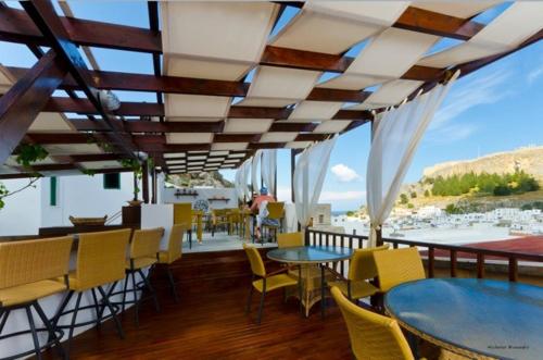 a restaurant with tables and chairs and a view of the ocean at Xenones Lindos in Líndos
