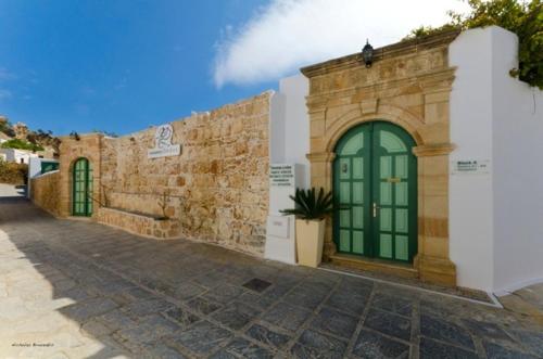 a stone building with a green door on a street at Xenones Lindos in Líndos