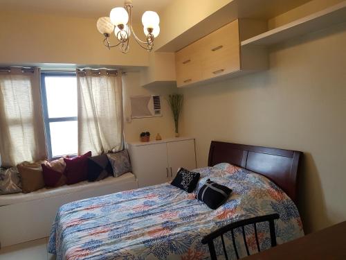 a bedroom with a bed and a window with a couch at KC Studio 5 at Horizon 101 Cebu in Cebu City