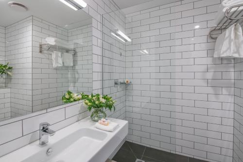 a white bathroom with a sink and a mirror at Sudima Hotel Christchurch Airport in Christchurch