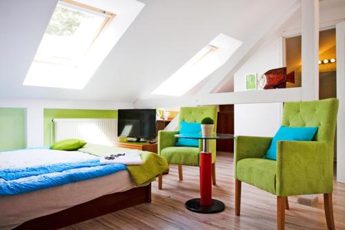 a bedroom with a bed and two chairs and a tv at Willa Przy Plaży in Pogorzelica