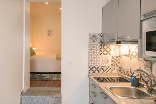 uma cozinha com um lavatório e um quarto com uma cama em À Francos Love Lair 2 em Porto
