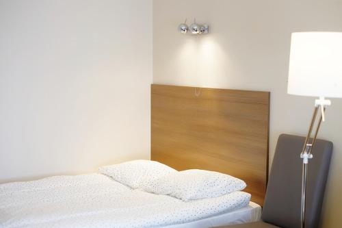 a bedroom with a bed with a lamp and white sheets at Domek Letniskowy Pod Lasem in Gdańsk