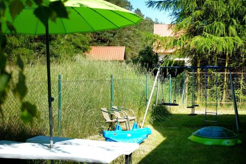 a swing set with two chairs and an umbrella at Domek Letniskowy Pod Lasem in Gdańsk