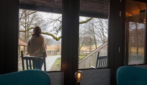 a woman looking out the window of a house at Bed & breakfast Hoeve Springendal in Hezingen