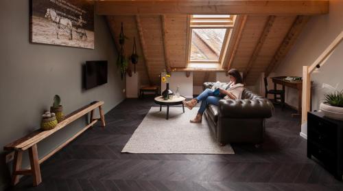a woman sitting on a couch in a living room at Bed & breakfast Hoeve Springendal in Hezingen