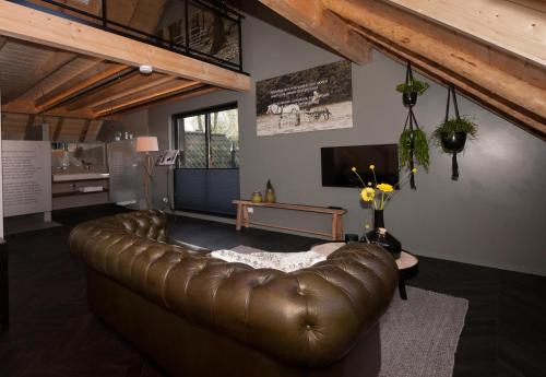a leather couch in a living room with a television at Bed & breakfast Hoeve Springendal in Hezingen