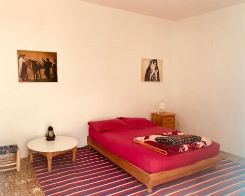 a bedroom with a red bed and a table at Gite Le Nomade in Mirleft